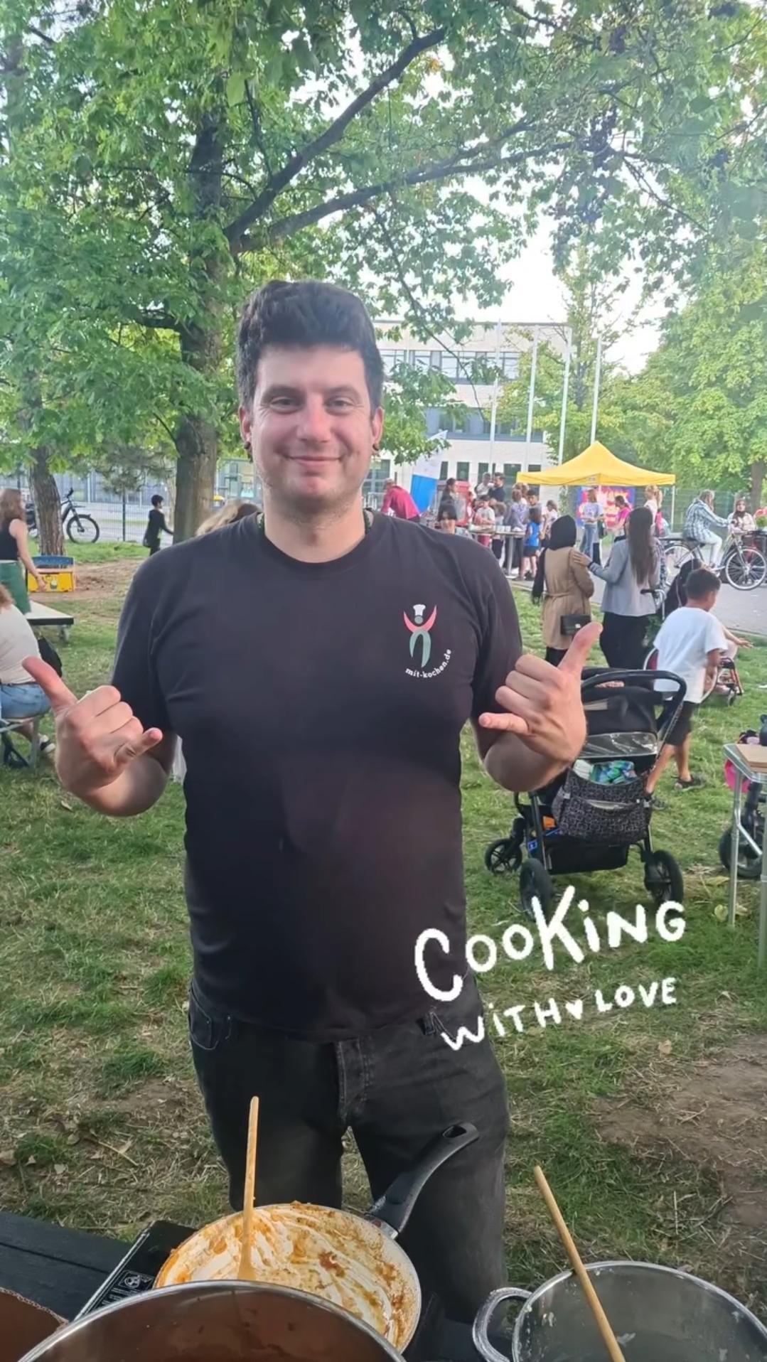 Peter Kartoffel grinst hinter seinen Töpfen im Park – Cooking with Love