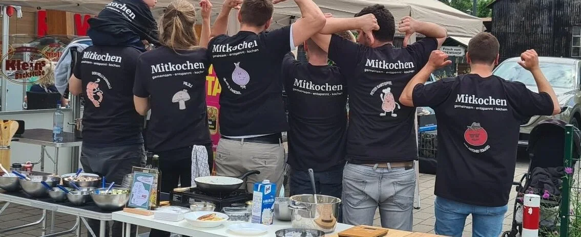Die Mitkochen-Crew reckt zusammen die Arme in die Höhe
